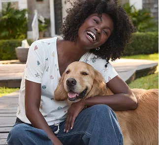 A woman wearing a white top petting a golden retriever.