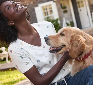 A woman wearing a white petting a golden retriever.