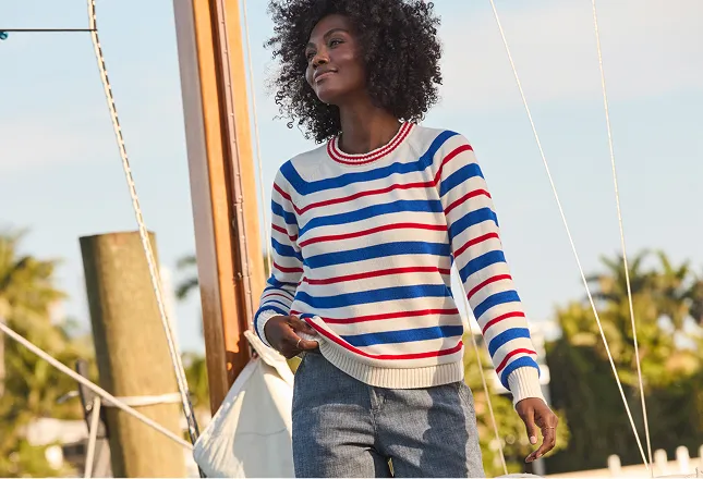 Woman wearing a white sweater with blue and orange horizontal stripes.