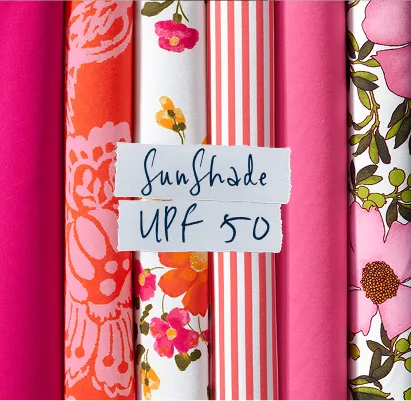 Torn paper that is labeled: SunShade UPF 50. A closeup of folded, patterned fabrics.