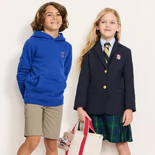 A boy wearing a blue hoodie and a girl wearing a uniform jacket and a tartan skirt.