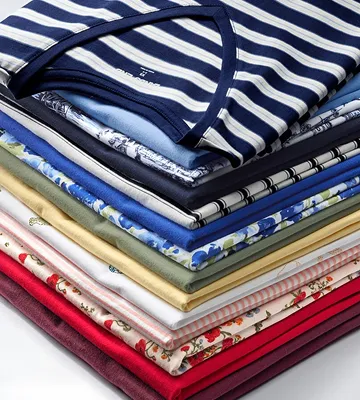 A stack of folded tops in different colors and patterns.