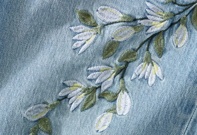 Close up of floral embroidery on a pair of jeans.