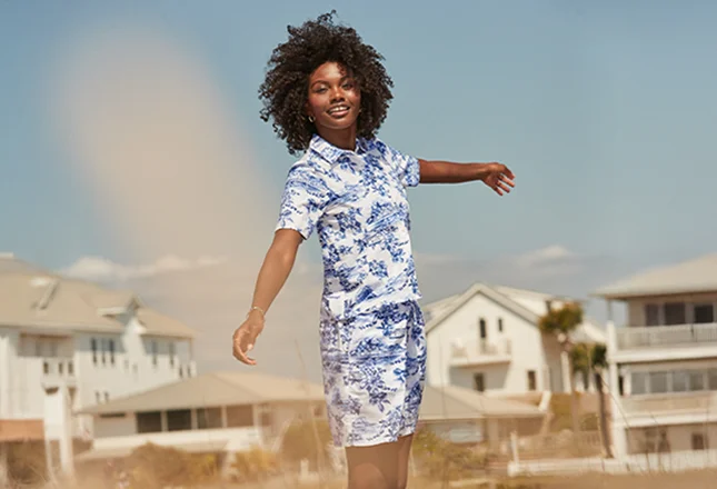 A woman wearing a white and navy floral pattern shirt and shorts.
