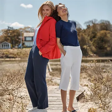 Two women standing back-to-back in a field.
