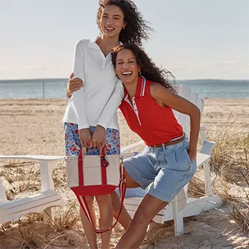Two women wearing supima polos on a beach.
