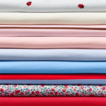 A folded stack of t-shirts in different colors and patterns.