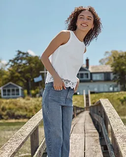 A woman wearing denim jeans on a wooden bridge.