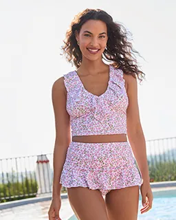 A woman wearing a floral pattern swim top and bottom at a pool.