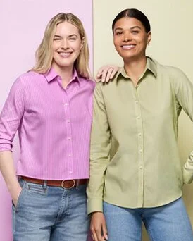 Two women wearing button down shirts stand next to each other.