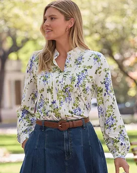 A woman wearing a white top with blue and green floral patterns.