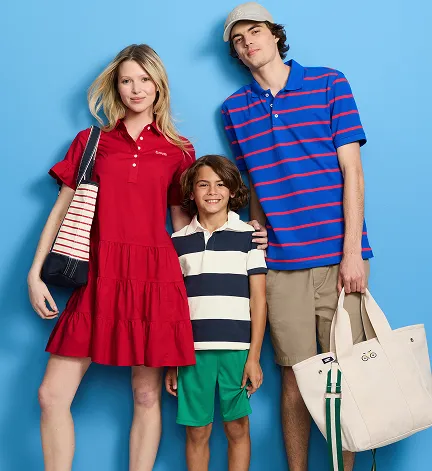 A woman wearing a red dress, a man wearing a blue and red striped polo and a boy wearing a white and navy striped polo.