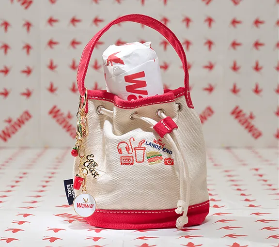 A canvas tote with red accents, WAWA embroidery and a wrapped sandwich stuff inside.