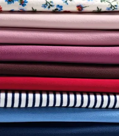 A stack of fleece clothes in differetn colors and patterns.