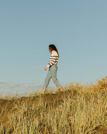A woman walking through a straw field.