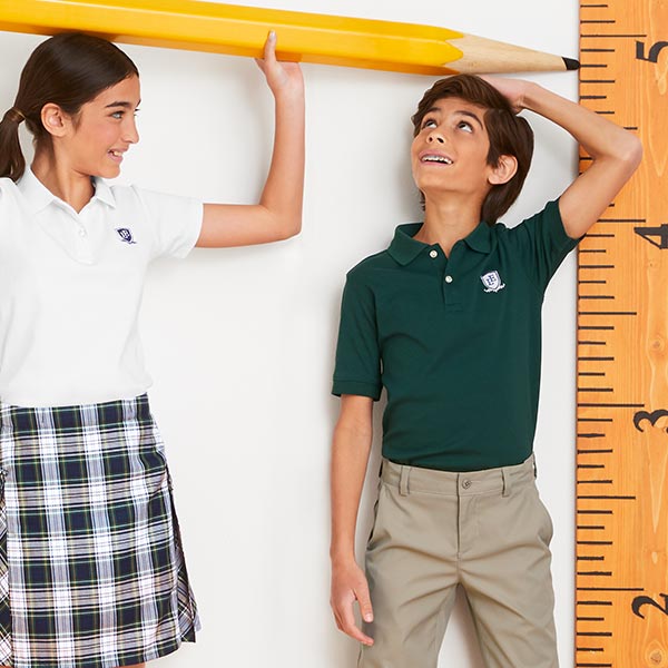 A girl marking a boys height with an exaggeratedly sized pencil and ruler.