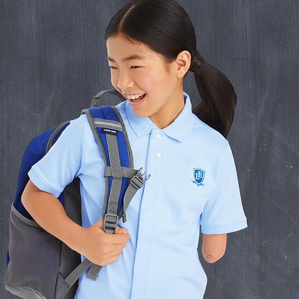 A girl smiles while wearing her backpack.