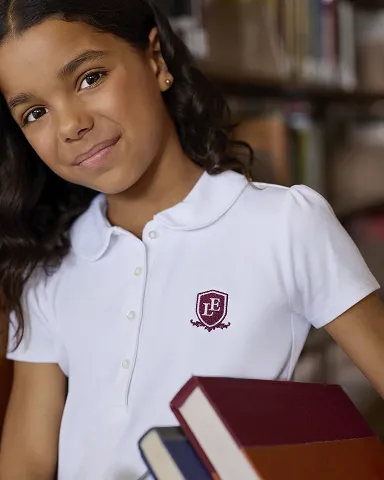 Student wearing a a white polo holding textbooks.