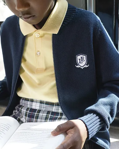 A student wearing a white polo with a backpack over her right shoulder.