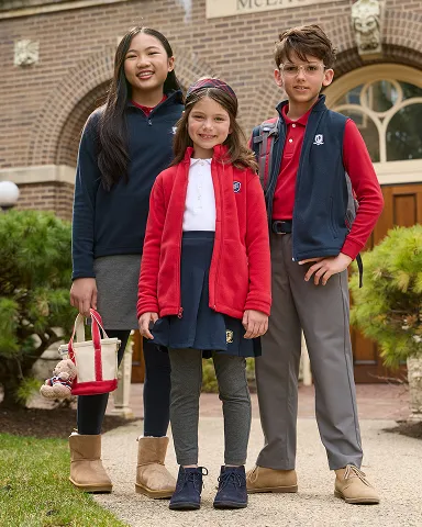 Three students stand outside of a school building.