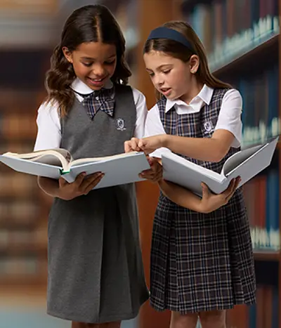 Two students wearing gray skirts reading textbooks.